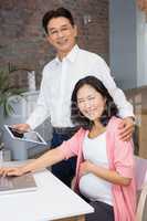 Happy man showing tablet to his pregnant wife