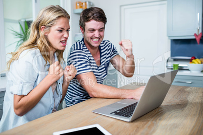 Happy couple watching videos on laptop