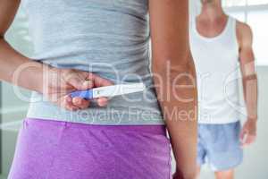 Woman hiding pregnancy test behind her back