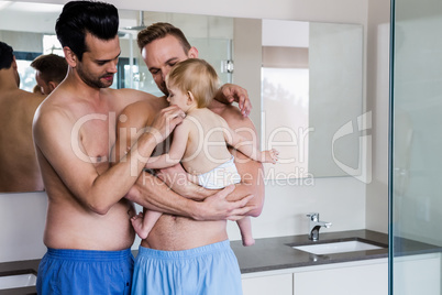 Happy gay couple holding their child