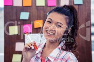 Smiling woman against wooden wall with notes on it