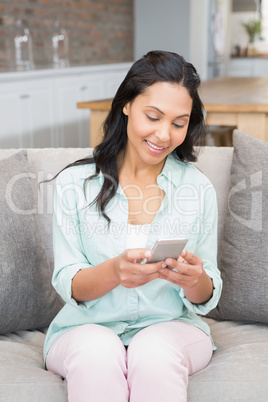 Smiling brunette using smartphone