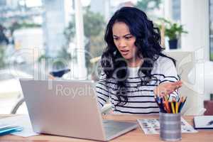 Frowning Asian woman looking at laptop