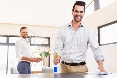 Smiling gay couple cleaning living room
