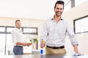 Smiling gay couple cleaning living room