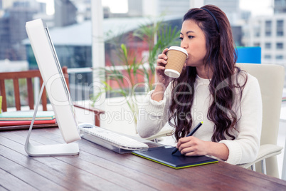 Asian woman drinking and using digital board while looking at co