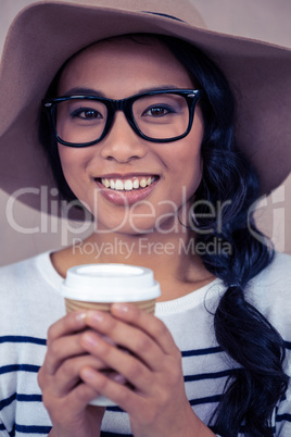 Attractive Asian woman with hat holding disposable cup