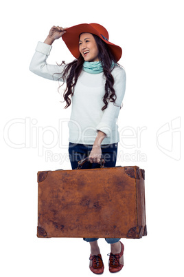 Smiling Asian woman holding luggage holding hat