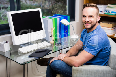 Smiling designer posing while sitting at desk