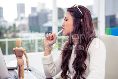 Focused Asian woman with pen on chin