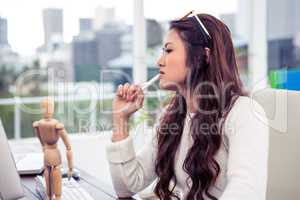 Focused Asian woman with pen on chin