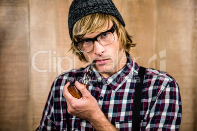 Serious blond hipster smoking a pipe