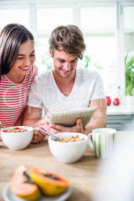 Happy couple using tablet and having breakfast