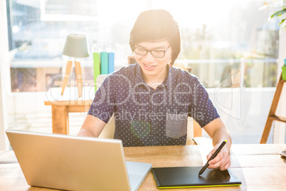 Smiling hipster businessman using laptop and graphic tablet