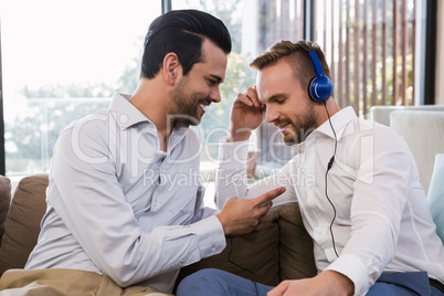 Smiling gay couple relaxing in living room