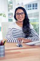 Smiling Asian woman sitting at desk posing for camera
