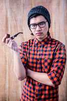 Serious hipster holding a pipe with crossed arms