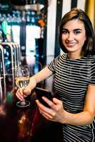 Portrait of woman having a drink and using smartphone