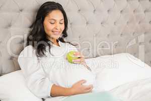 Pregnant brunette holding apple