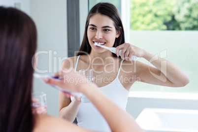 Smiling brunette brushing teeth