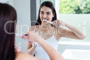 Smiling brunette brushing teeth