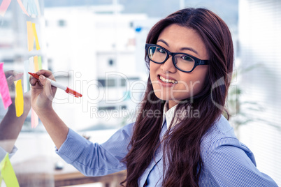 Asian businesswoman using sticky notes on wall