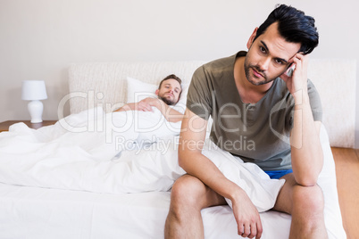 Thoughtful man sitting on bed