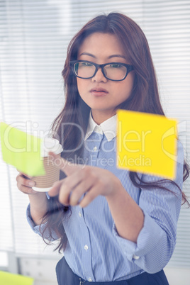 Asian businesswoman using sticky notes on wall