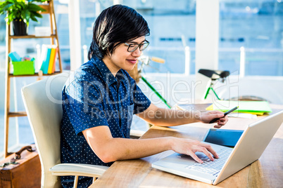 Smiling hipster businessman using laptop