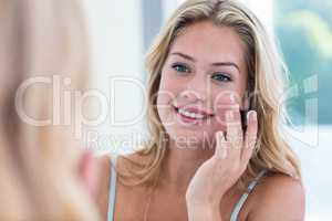 Smiling pretty woman applying cream on her face