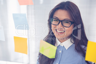 Asian businesswoman using sticky notes on wall