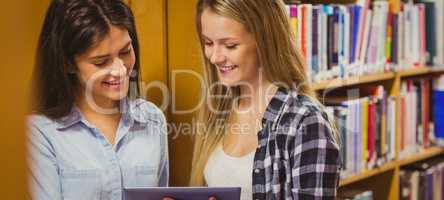 Pretty young students working together with tablet