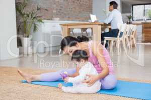 Happy mother and baby daughter sitting on exercising mat