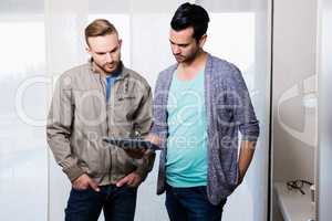 Focused gay couple looking at tablet