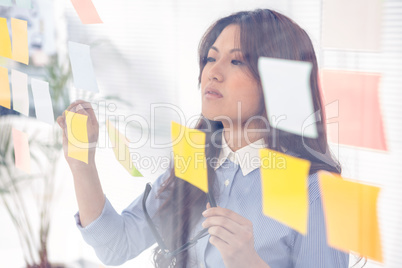 Asian businesswoman using sticky notes on wall