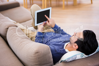 Man using tablet lying on the couch