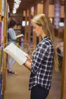 Serious students reading next to bookshelf