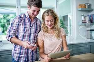 Cute couple using tablet computer in the kitchen