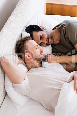 Happy gay couple lying on bed