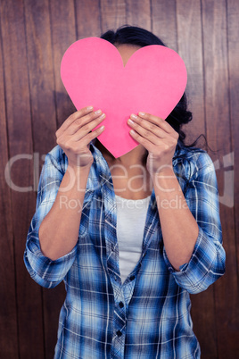 Woman hiding her face behind paper heart