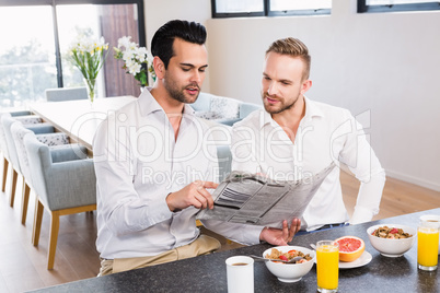 Smiling gay couple reading newspaper