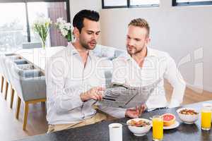 Smiling gay couple reading newspaper