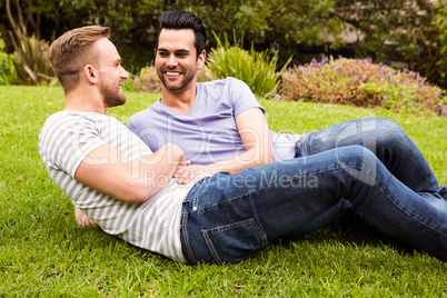 Happy gay  couple lying on grass