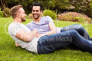 Happy gay  couple lying on grass