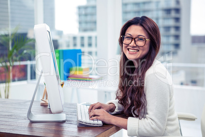 Smiling Asian woman on computer looking at the camera