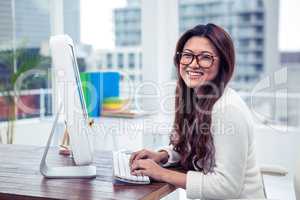 Smiling Asian woman on computer looking at the camera