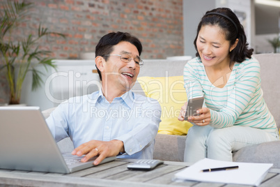 Smiling woman showing smartphone to her husband