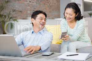 Smiling woman showing smartphone to her husband