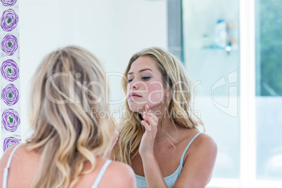 Focused beautiful young woman looking at herself in the bathroom