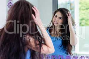 Unsmiling brunette looking her reflection in the mirror